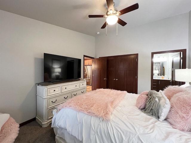 bedroom featuring dark colored carpet, ensuite bath, a ceiling fan, and baseboards