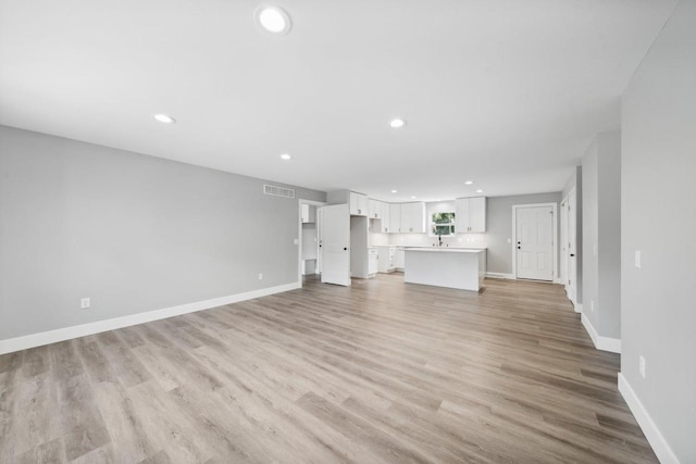 unfurnished living room with light wood-type flooring, recessed lighting, visible vents, and baseboards