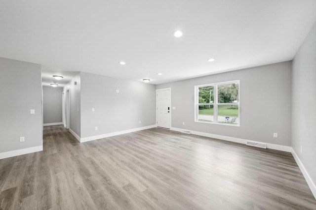 empty room featuring baseboards, visible vents, wood finished floors, and recessed lighting