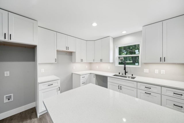 kitchen featuring recessed lighting, dark wood-type flooring, a sink, baseboards, and white cabinets