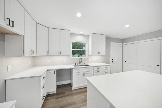 kitchen with recessed lighting, light countertops, white cabinets, a sink, and light wood-type flooring