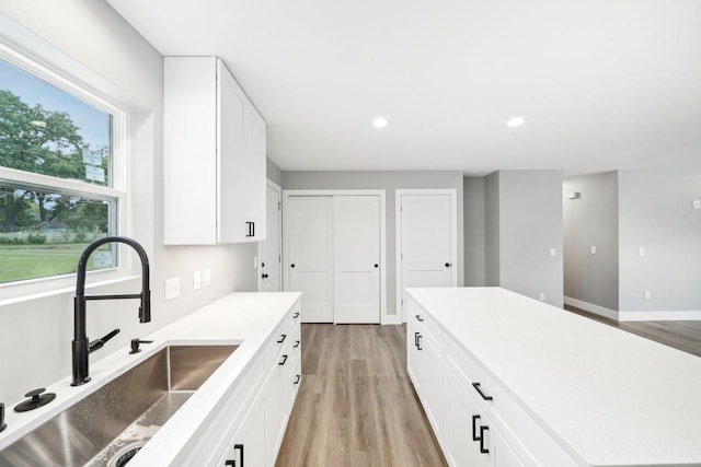 kitchen with a sink, light wood-style flooring, and white cabinetry