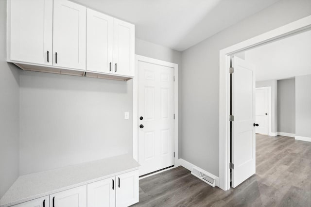 mudroom featuring baseboards, visible vents, and dark wood-type flooring