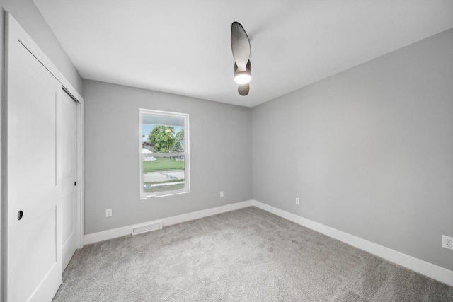 unfurnished bedroom featuring baseboards, visible vents, ceiling fan, carpet floors, and a closet