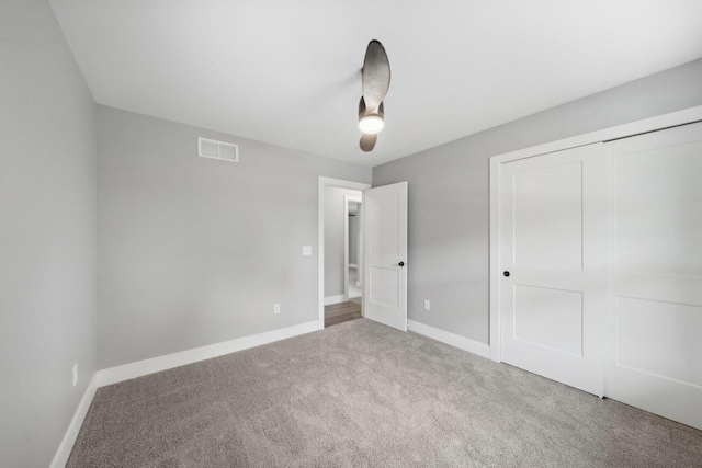 unfurnished bedroom featuring carpet floors, baseboards, visible vents, and a closet