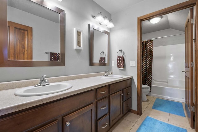 bathroom with toilet, double vanity, a sink, and tile patterned floors