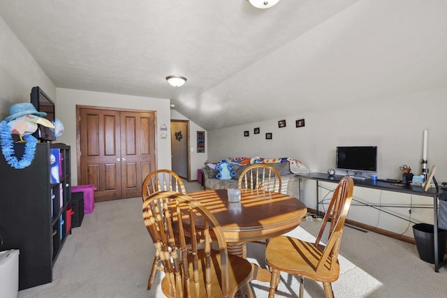 dining area with lofted ceiling and light colored carpet