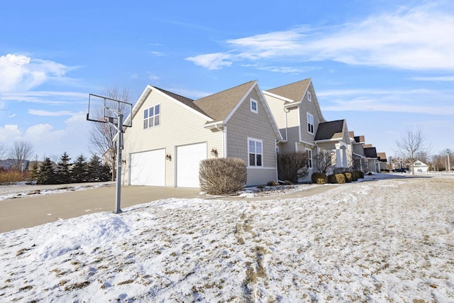 view of snow covered exterior with a garage and a residential view