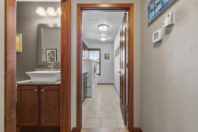 corridor featuring baseboards, a sink, and independent washer and dryer