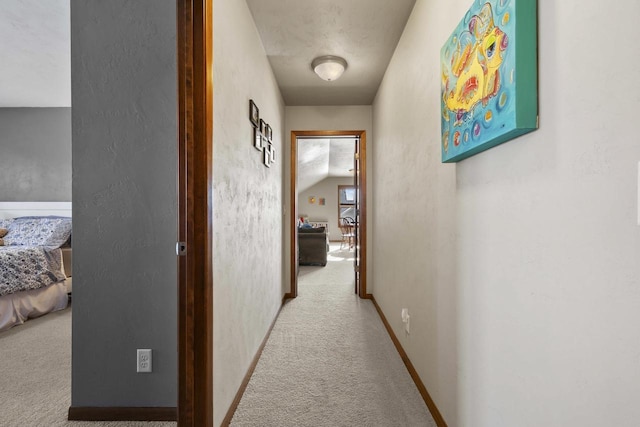 corridor with carpet flooring, a textured wall, and baseboards