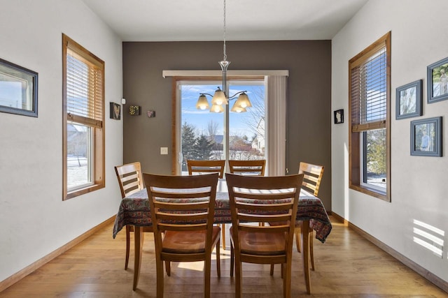 dining area featuring a notable chandelier, baseboards, and light wood-style floors