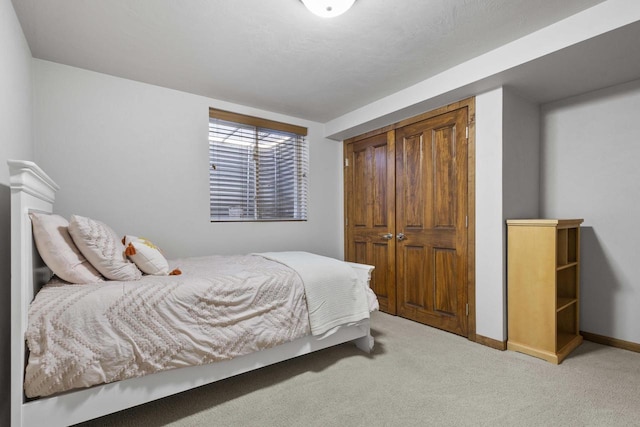 carpeted bedroom featuring baseboards and a closet