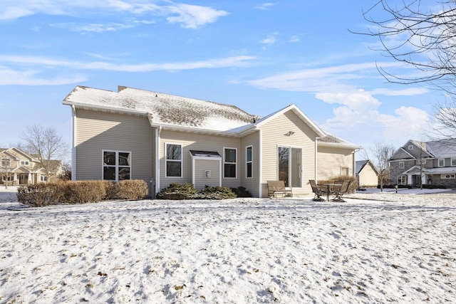 snow covered back of property featuring entry steps