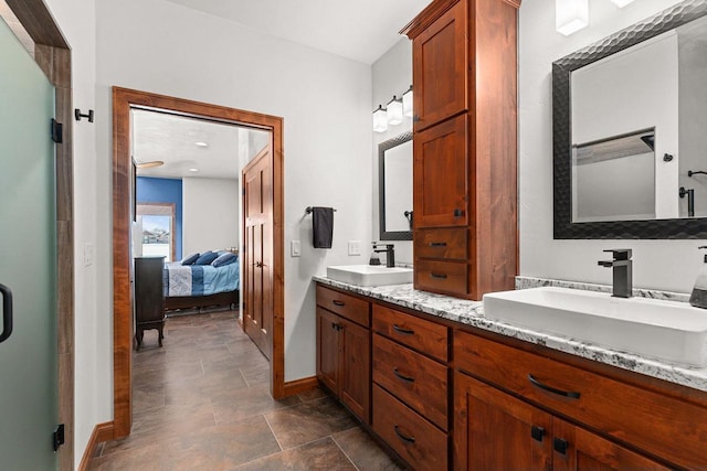 bathroom featuring double vanity, a sink, baseboards, and ensuite bathroom