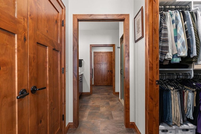 corridor with stone finish floor and baseboards