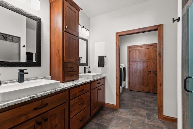 bathroom featuring double vanity, baseboards, washer / clothes dryer, and a sink