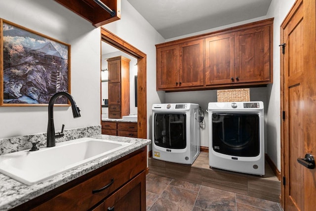 laundry area with cabinet space, separate washer and dryer, and a sink