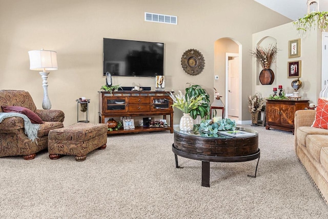 carpeted living room featuring arched walkways and visible vents