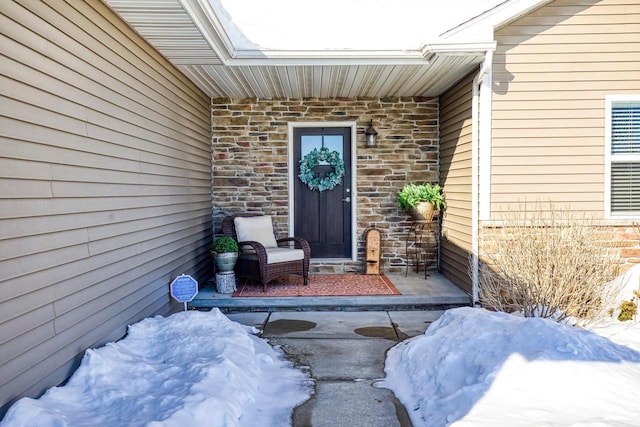 snow covered property entrance with brick siding