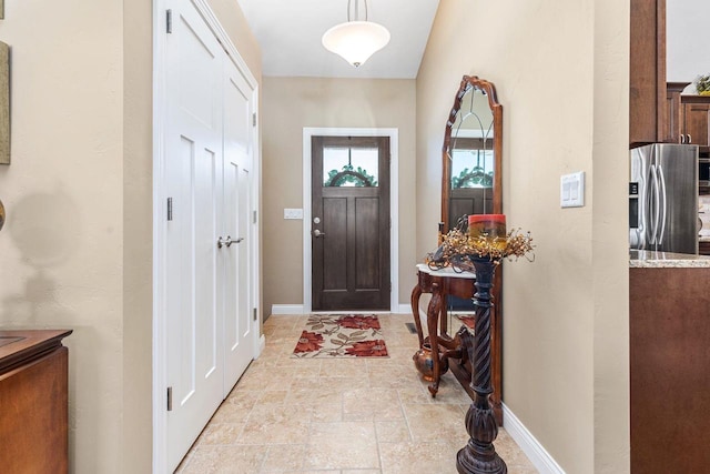 foyer with stone finish floor and baseboards