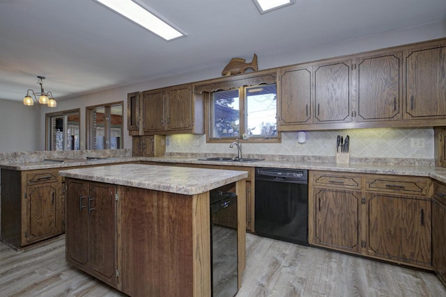 kitchen with a peninsula, a sink, light wood-style floors, black dishwasher, and light countertops