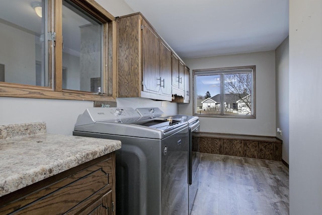 laundry area featuring washer and dryer, cabinet space, and wood finished floors