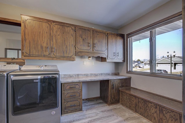 laundry area with light wood-type flooring, cabinet space, and washer and clothes dryer