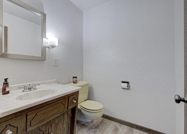 bathroom with baseboards, vanity, toilet, and wood finished floors