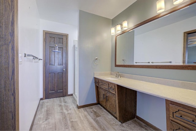 full bathroom featuring baseboards, walk in shower, wood finished floors, and vanity