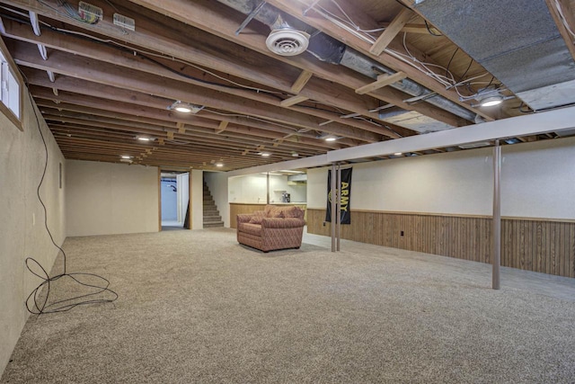 finished basement featuring stairs, wooden walls, wainscoting, and carpet