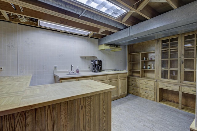 kitchen featuring wood counters, white stovetop, under cabinet range hood, open shelves, and a sink