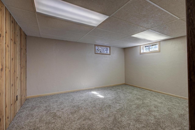 below grade area with baseboards, carpet flooring, and a drop ceiling