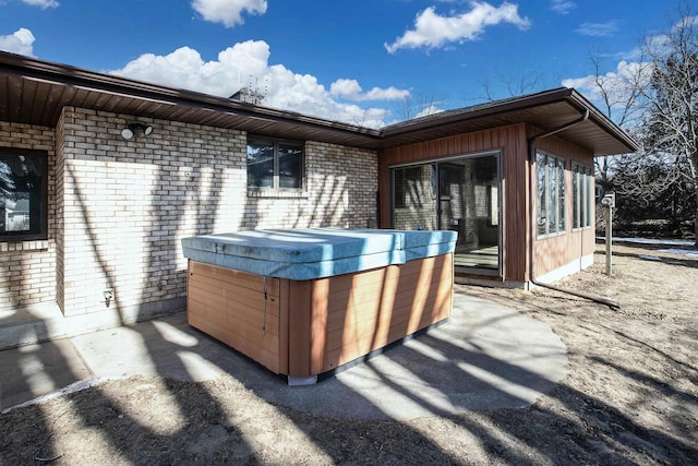 exterior space featuring a hot tub and brick siding