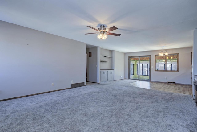 interior space featuring baseboards and ceiling fan with notable chandelier