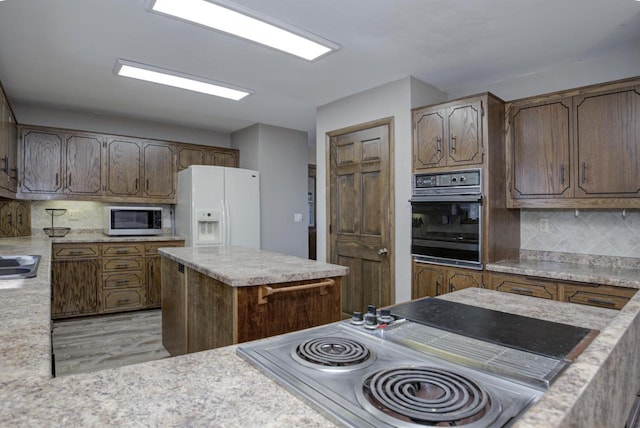 kitchen featuring tasteful backsplash, a kitchen island, appliances with stainless steel finishes, light countertops, and a sink