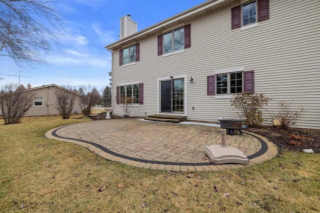 rear view of property with entry steps, a yard, a chimney, and a patio area