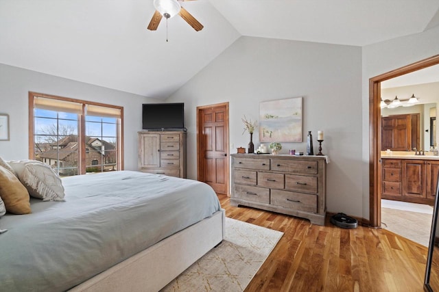 bedroom with lofted ceiling, ceiling fan, light wood-style flooring, a sink, and ensuite bath