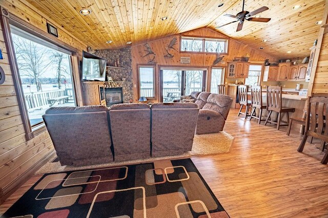 living area with wooden ceiling, a fireplace, light wood-style flooring, and wooden walls