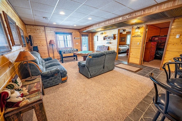 living room featuring recessed lighting, a paneled ceiling, and wooden walls