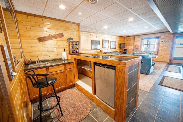 kitchen featuring wooden walls, refrigerator, a sink, open floor plan, and brown cabinetry