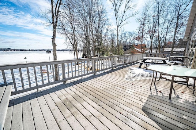 deck with a water view and outdoor dining area