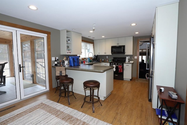 kitchen with electric stove, open shelves, visible vents, light wood-style flooring, and a peninsula