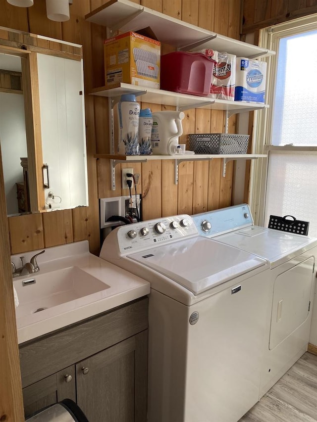 washroom featuring light wood-type flooring, a sink, cabinet space, and washer and dryer