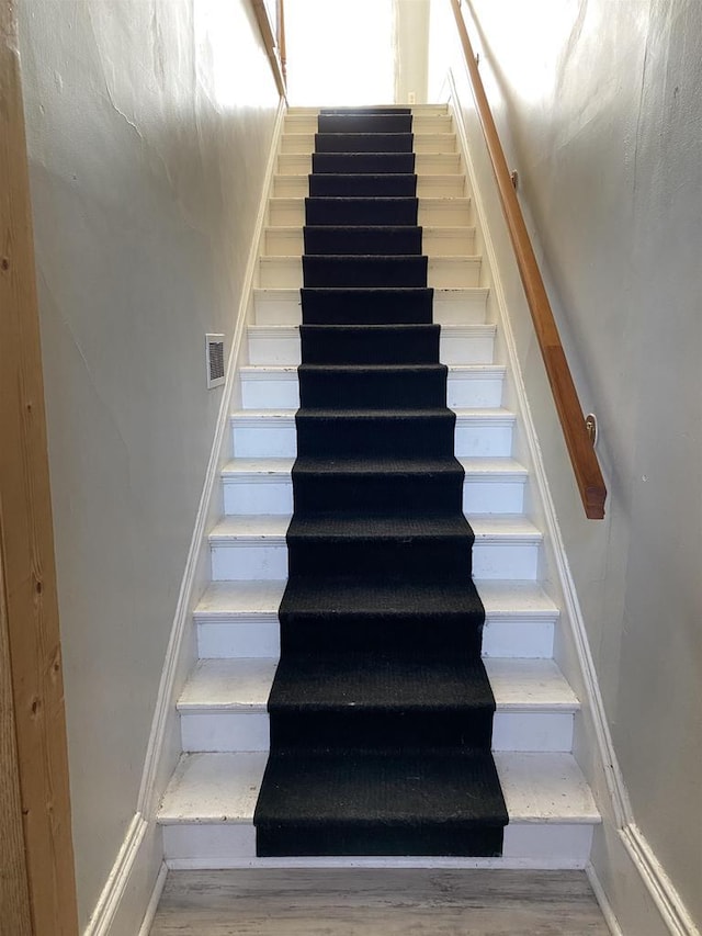 stairs with wood finished floors, visible vents, and baseboards