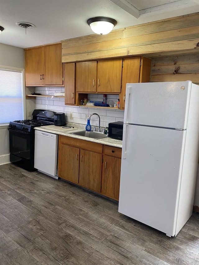 kitchen with tasteful backsplash, dark wood-type flooring, light countertops, black appliances, and a sink