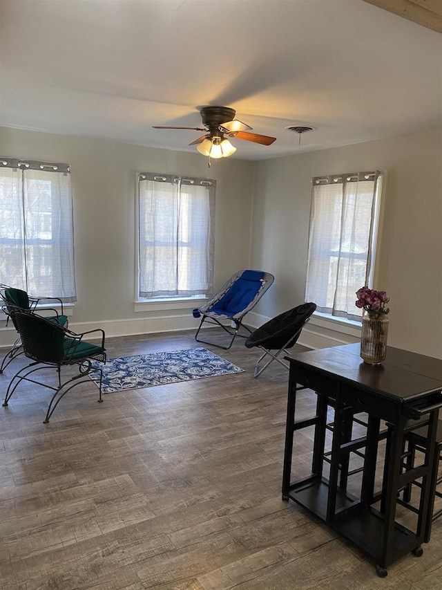 dining room with baseboards, visible vents, ceiling fan, and wood finished floors