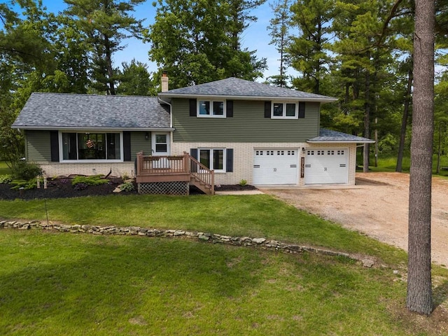 split level home with driveway, brick siding, a chimney, and a front yard