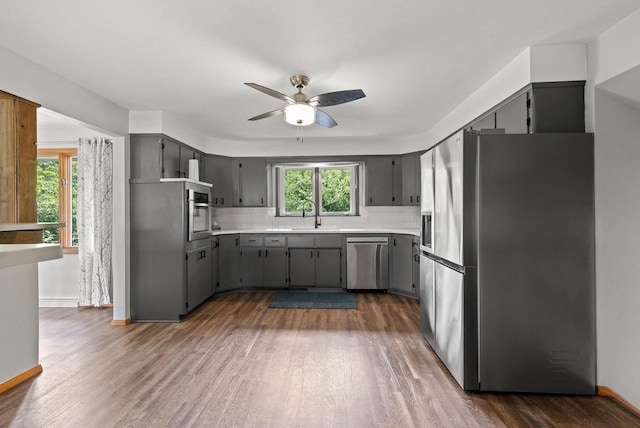 kitchen featuring stainless steel appliances, dark wood-style flooring, gray cabinets, and backsplash