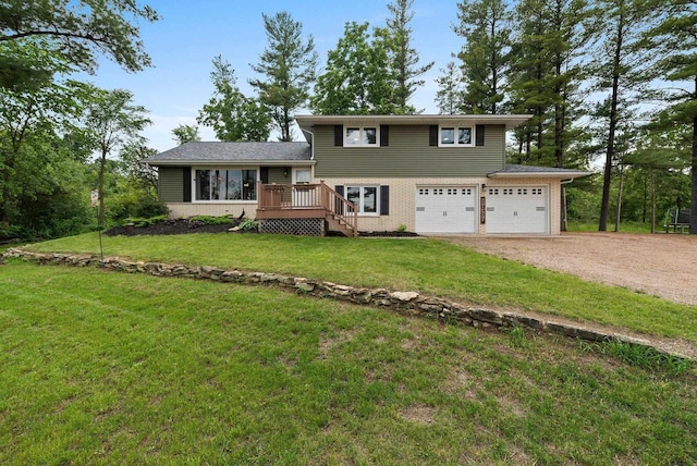 split level home featuring dirt driveway, an attached garage, a deck, a front lawn, and brick siding