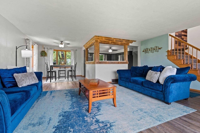 living room featuring stairs, wood finished floors, and baseboards